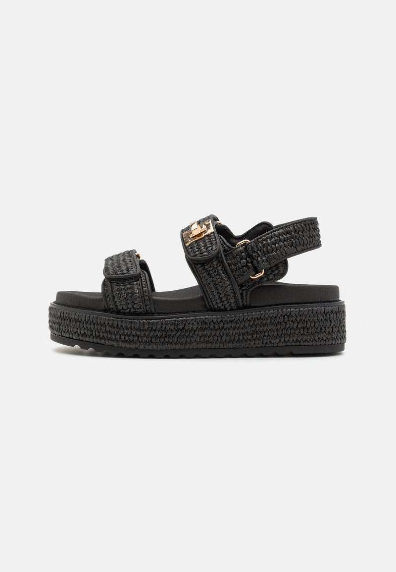 Schwarze Plateausandalen mit geflochtenen Riemen, verstellbaren Schnallen und einer dicken strukturierten Sohle für Griff und Stabilität. Minimalistisches Design.