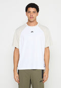 Weißes T-Shirt mit kurzen Ärmeln und beigen Raglanärmeln, mit rundem Ausschnitt und dezentem Nike-Logo auf der Brust, aus glattem Stoff gefertigt.