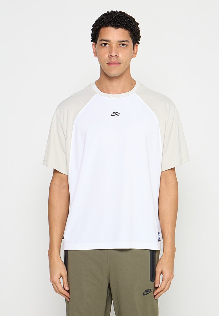 Weißes T-Shirt mit kurzen Ärmeln und beigen Raglanärmeln, mit rundem Ausschnitt und dezentem Nike-Logo auf der Brust, aus glattem Stoff gefertigt.