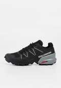Schwarzer Salomon Trailrunning-Schuh mit robustem Profil, weißem Logo an der Seite, verstärkter Zehenkappe und grauem Fersenbereich mit rotem Contagrip-Label.