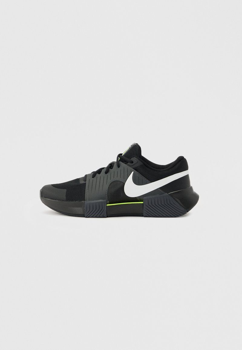Schwarz-grauer Sportschuh mit weißem Nike-Swoosh und neon-grünem Akzent auf der Zwischensohle, Mesh-Obermaterial und strukturierter Sohle.