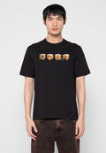 Schwarzes Baumwoll-T-Shirt mit einem grafischen Druck von vier würfelförmigen Designs mit bunten Illustrationen auf der Vorderseite. Kurze Ärmel, Rundhalsausschnitt.