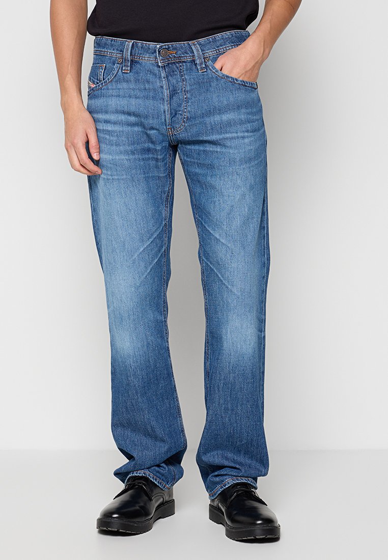 Hellblaue Jeans aus Denim mit geradem Bein, fünf Taschen und sichtbaren Steppdetails. Kombiniert mit einem schwarzen Shirt und Schuhen.