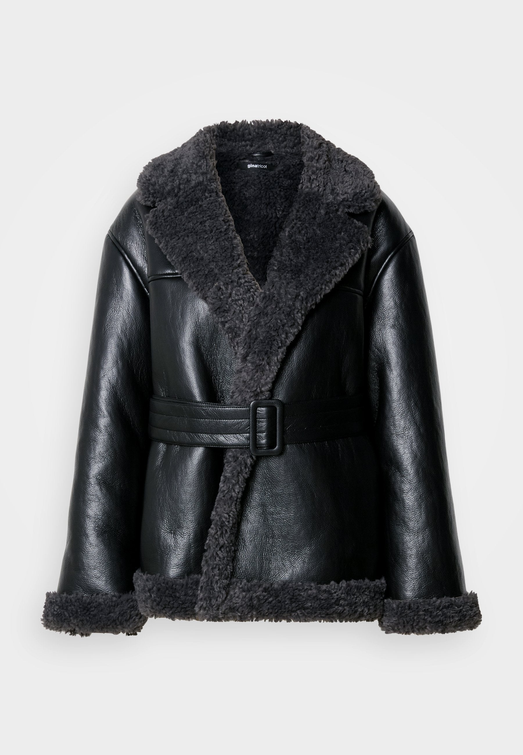 Schwarze Lammfelljacke mit einem breiten Kragen, strukturiertem grauen Futter, vorderem Schnallenriemen und plüschigen Bündchen.