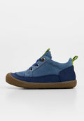 Kinderschuh mit niedrigem Schaft aus blauem Wildleder und Textil, mit brauner Gummisohle, marineblauen Akzenten, blauen Schnürsenkeln und grünen Zuglaschen.