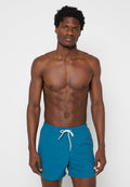 Türkisfarbene Badeshorts aus leichtem Material, mit einem elastischen Bund und weißem Kordelzug sowie einer bequemen Passform.
