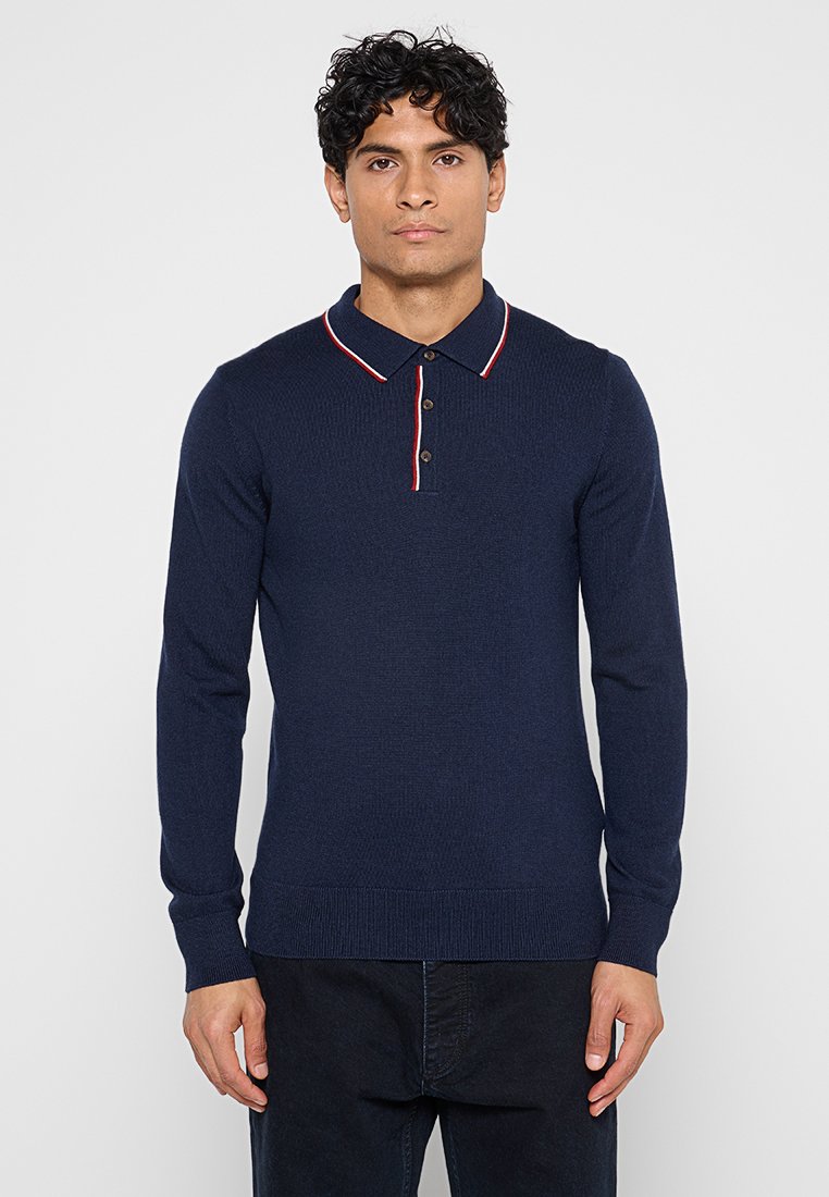 Marineblaues Polohemd mit langem Arm und gerippter Struktur, kontrastierendem roten und weißen Kragen sowie einer Knopfleiste mit drei Knöpfen. Hat eine taillierte Passform.