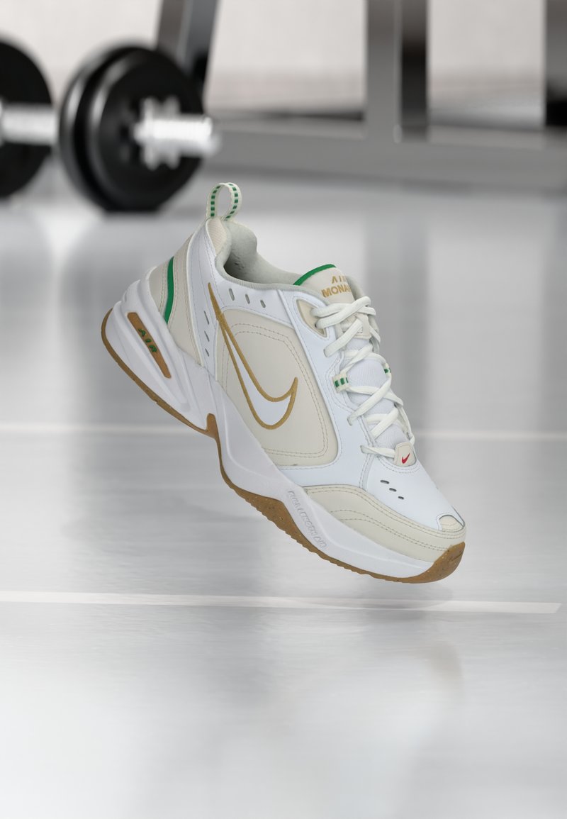 Weiße Sportschuhe mit einem strukturierten Obermaterial aus Leder, goldenem Nike-Swoosh, grünen Akzenten und einer Gummisohle. Verfügt über ein Schnürdesign und einen gepolsterten Saum.