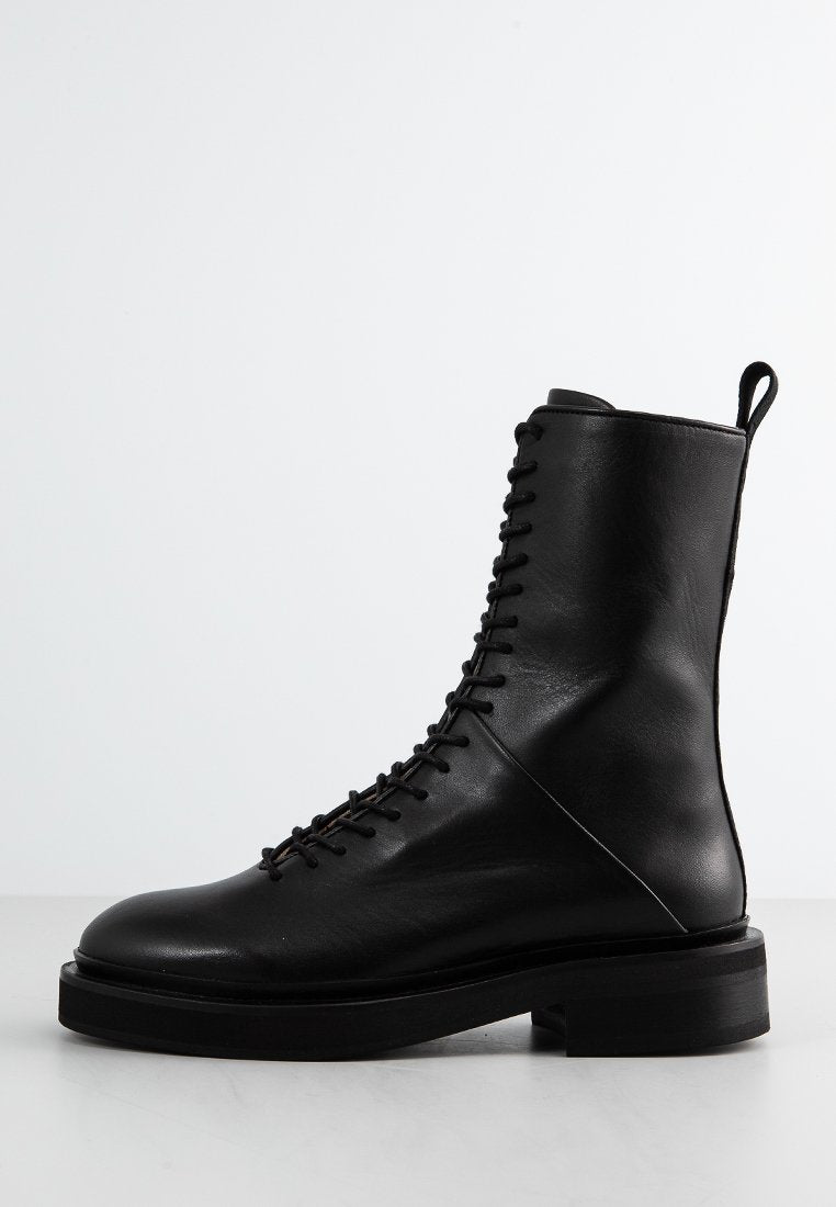 Schwarze Schnürstiefel aus Leder mit glatter Textur, abgerundeter Zehenpartie und dicker schwarzer Gummisohle. Verfügt über eine Schlaufe auf der Rückseite für ein einfaches Anziehen.