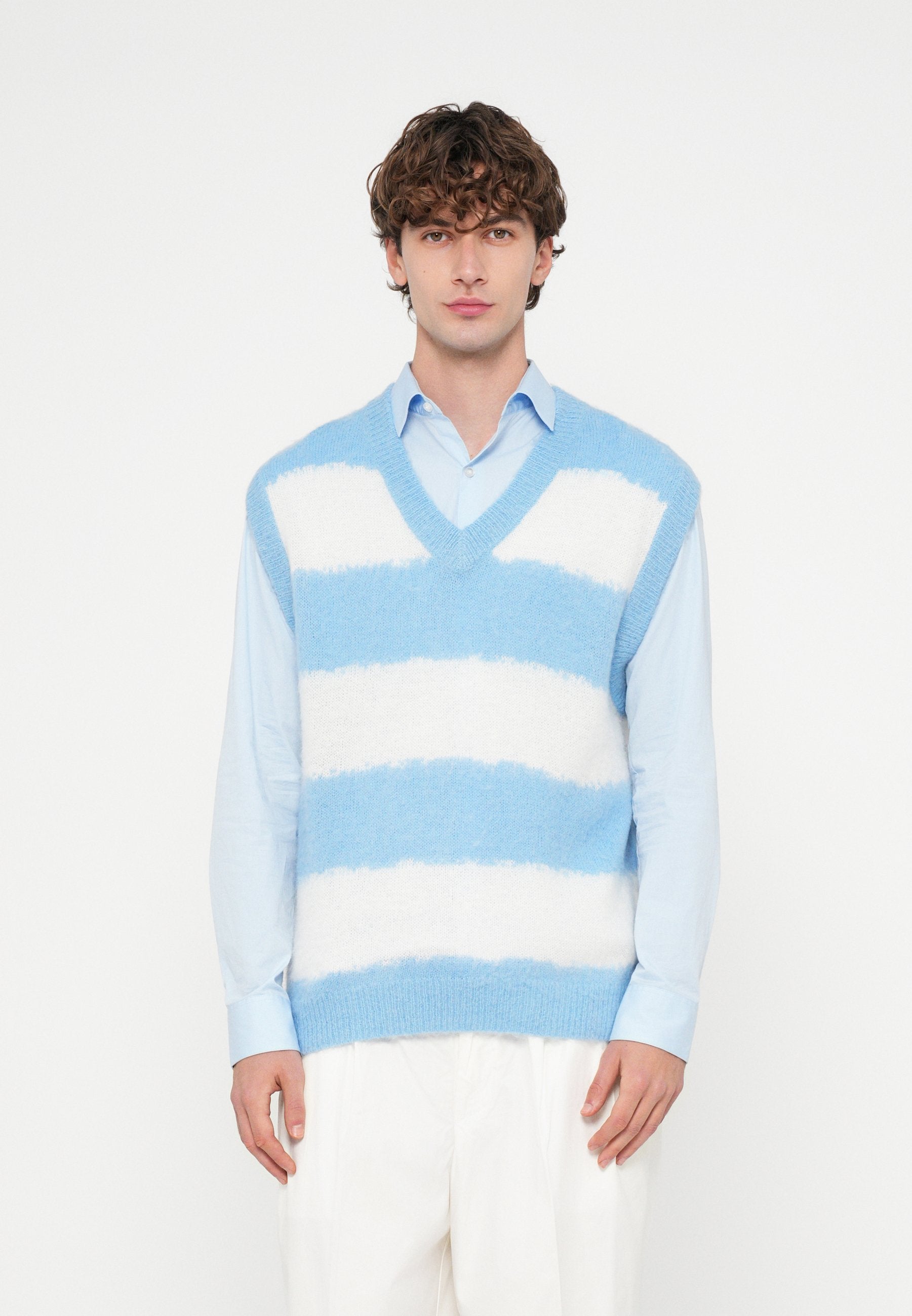 Hellblauer und weiß gestreifter, ärmelloser Strickpullover mit V-Ausschnitt, weich im Griff und mit breiten Streifen. Wird über einem hellblauen Hemd getragen.