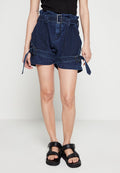 Blaue Denim-Shorts mit hoher Taille, verstellbarem Gürtel und Seitenschnürungen; verfügt über ein strukturiertes Muster und eine lockere Passform. Schwarze Plateausandalen.