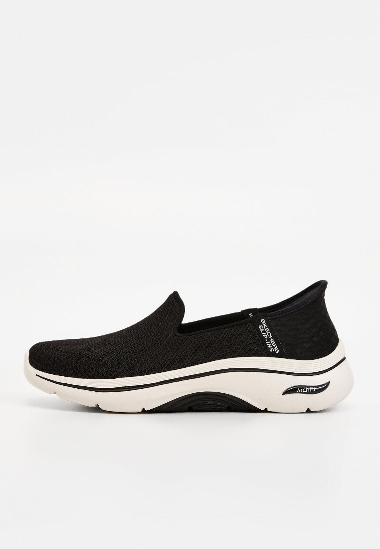 Schwarzer Slip-On-Sneaker von Skechers mit weißer, gepolsterter Sohle mit der Aufschrift "Arch Fit" und atmungsaktivem Mesh-Obermaterial, Seitenansicht.