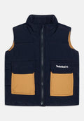 Marineblauer Steppweste mit hohem Kragen, zwei hellbraunen Taschen, Frontreißverschluss und Timberland-Logo auf der linken Tasche. Glatte Textur, isoliertes Design.