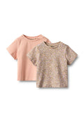 Zwei T-Shirts für Kinder mit kurzen Ärmeln: eines in einfarbig leichtem Rosa, das andere mit einem Blumenmuster in Pastellfarben auf einem beige Hintergrund.