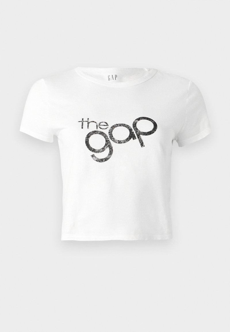 Weißes, kurz geschnittenes T-Shirt aus Baumwolle mit einem schwarzen Glitzer-Logo "the gap" auf der Vorderseite. Kurze Ärmel und runder Ausschnitt.