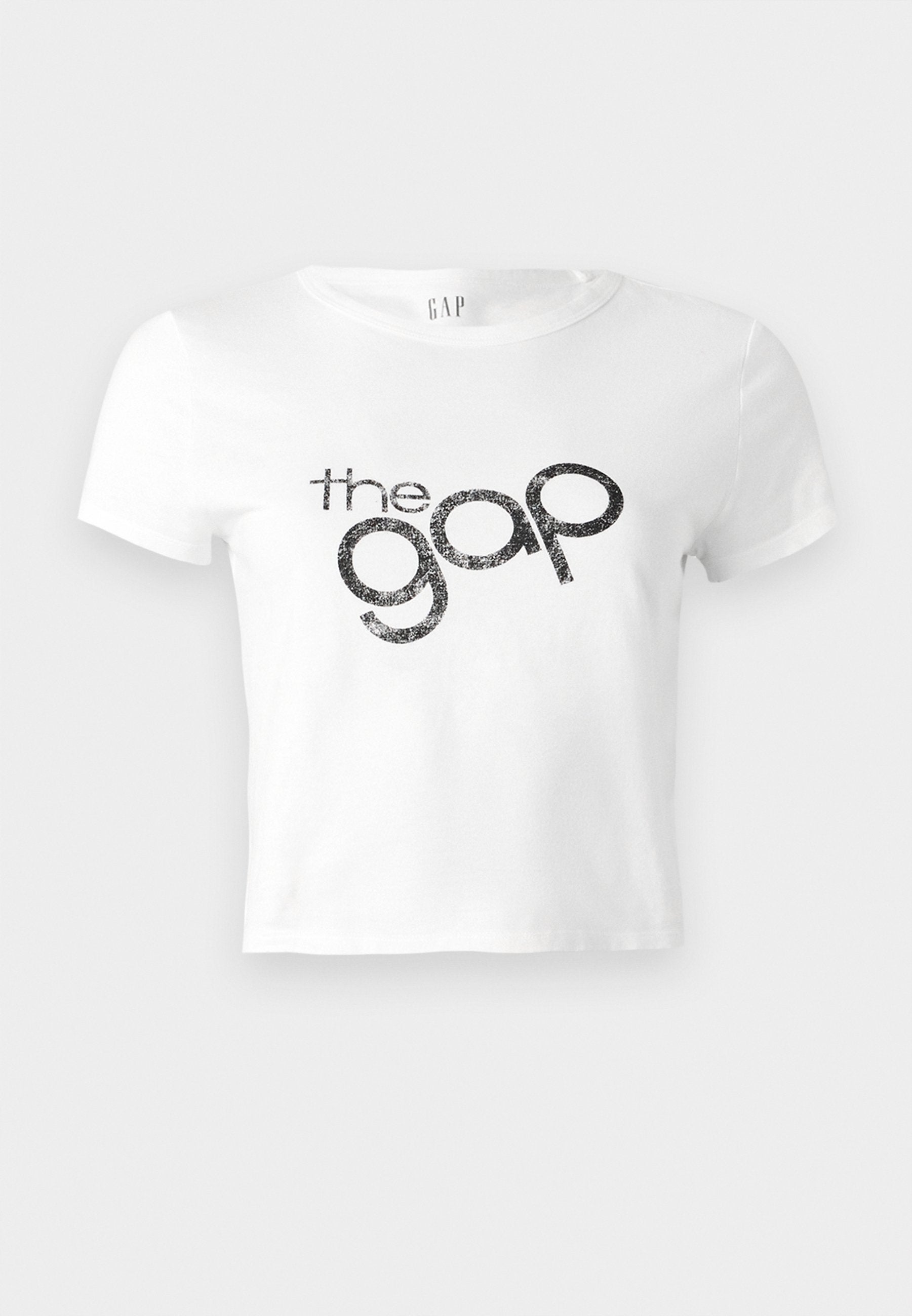 Weißes, kurz geschnittenes T-Shirt aus Baumwolle mit einem schwarzen Glitzer-Logo "the gap" auf der Vorderseite. Kurze Ärmel und runder Ausschnitt.