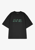 Schwarzes, oversized T-Shirt aus Baumwolle mit grünem Aufdruck, auf dem steht: "TEXTE MICH, WENN DU EINSAM BIST." Kurze Ärmel, klassischer Rundhalsausschnitt.