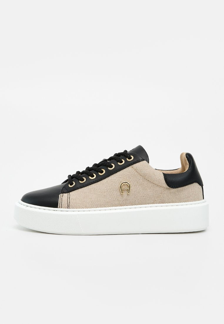 Beige und schwarze Sneaker mit niedrigem Schaft, weißer Plateausohle, schwarzen Schnürsenkeln, goldenen Ösen und kleinem goldenem Logo an der Seite.