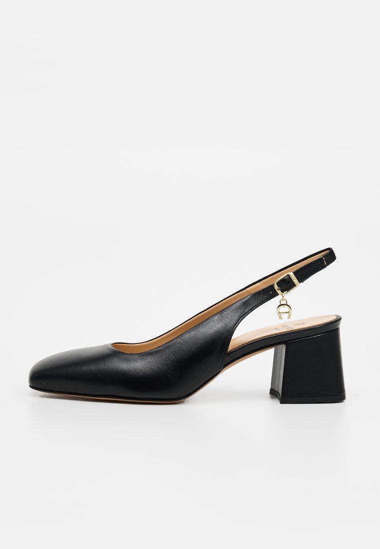 Schwarzer Lederslingback mit niedrigem Blockabsatz, spitzer Zehe und verstellbarem goldfarbenem Schnallenriemen auf weißem Hintergrund.
