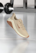 Beige Sportsschuh mit einem strukturierten Mesh-Obermaterial, einer hellen Zwischensohle und einer kontrastierenden braunen Außensohle, die ein dezentes Logo an der Seite aufweist.