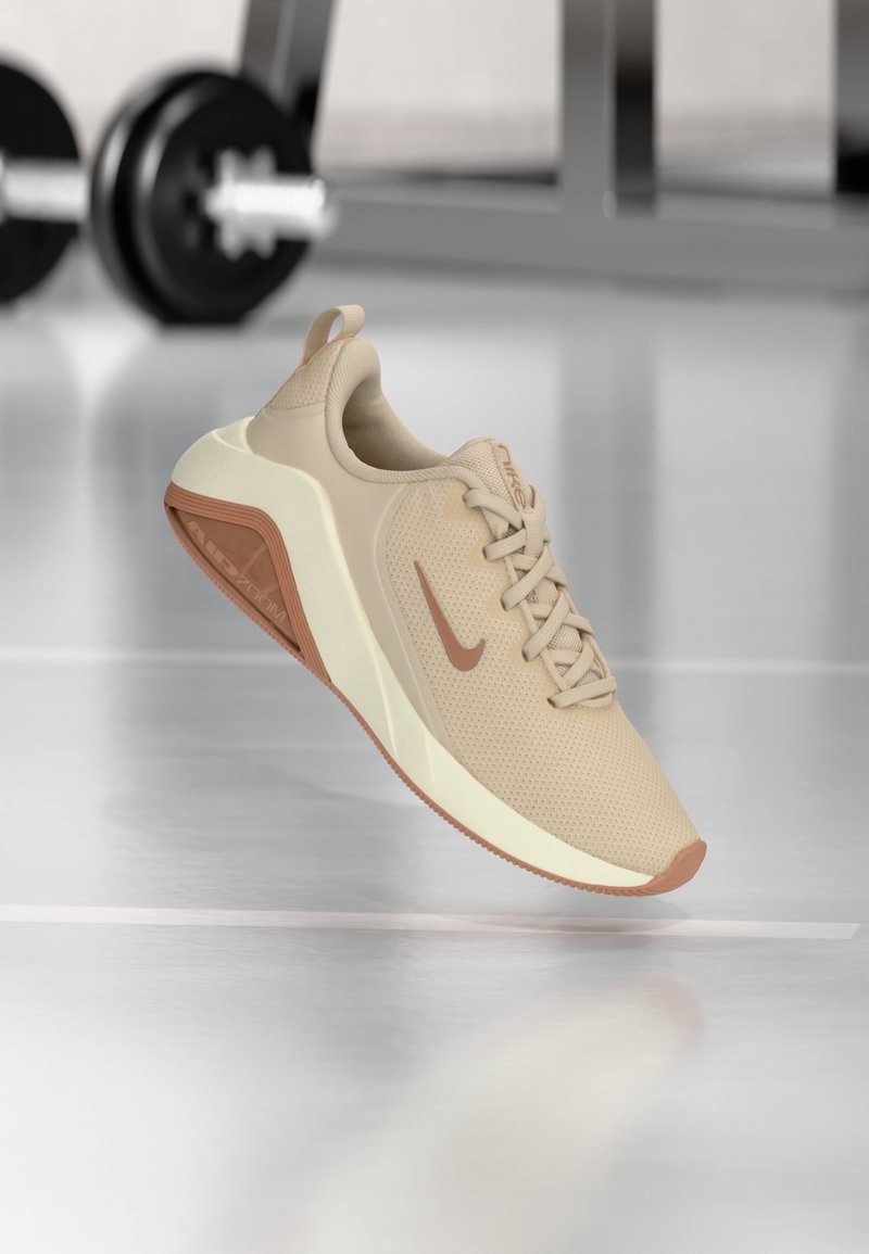 Beige Sportsschuh mit einem strukturierten Mesh-Obermaterial, einer hellen Zwischensohle und einer kontrastierenden braunen Außensohle, die ein dezentes Logo an der Seite aufweist.