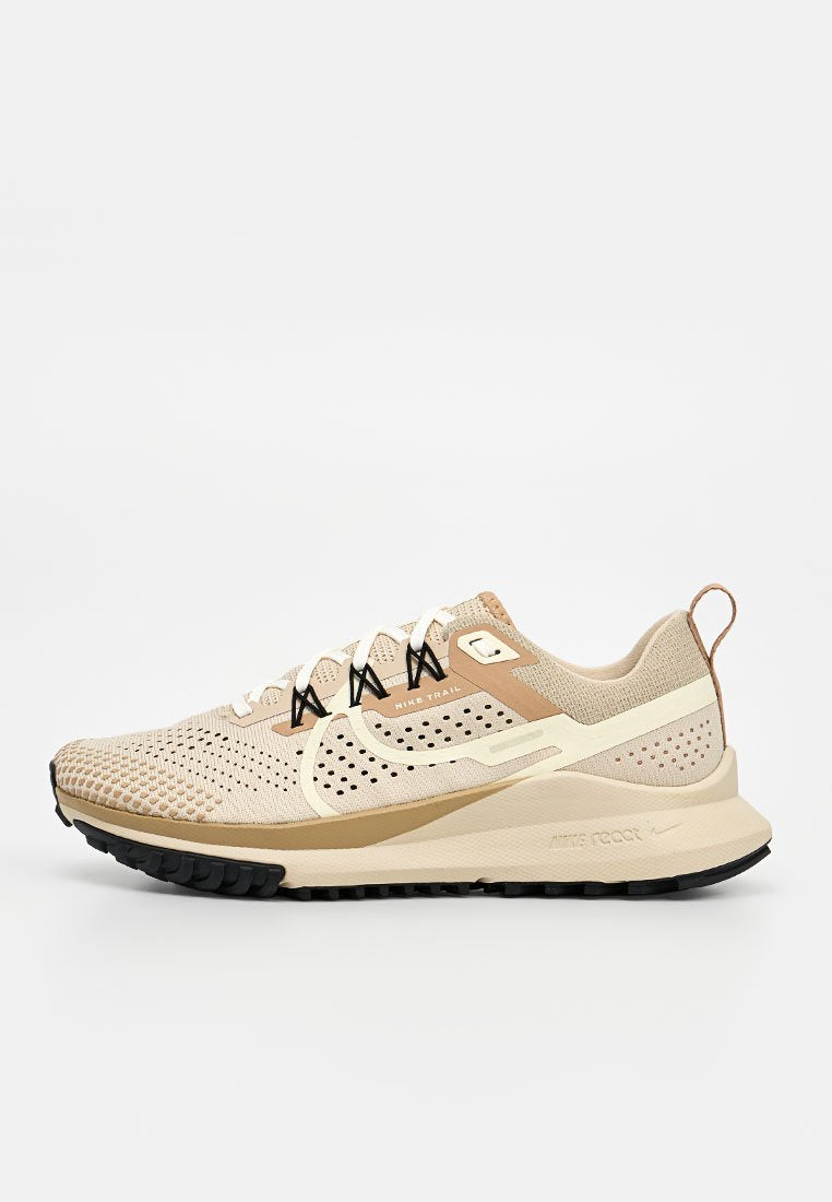 Beiger und hellbrauner Nike Trail Laufschuh mit atmungsaktivem Mesh, gepolsterter Sohle, schwarzer Profilsohle und Zuglasche an der Ferse, Seitenansicht.