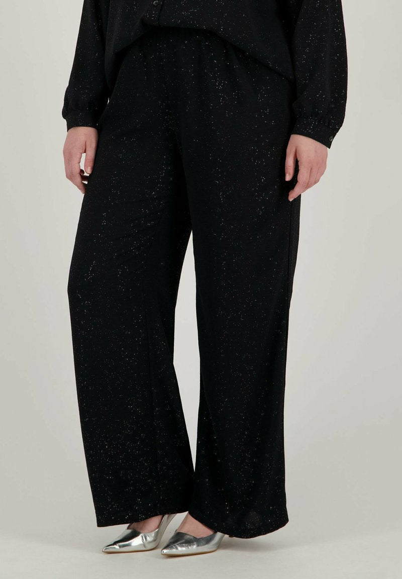 Schwarze weite Hosen mit weicher Textur und verstreuten silbernen Sprenkeln, kombiniert mit metallischen spitzen Ballerinas.