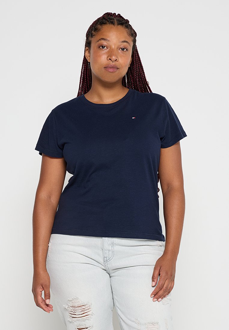 Marineblaue Baumwoll-T-Shirts mit kurzen Ärmeln, Rundhalsausschnitt und dezentem Logodetail auf der Brust. Getragen mit hellen Jeans mit abgewetzten Akzenten.
