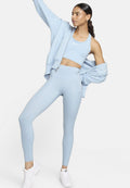 Helles blaues Sportoutfit bestehend aus einem verkürzten Tanktop, hoch geschnittenen Leggings mit Taschen und einem passenden oversize Sweatshirt.