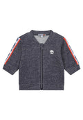 Dunkelgraue Zip-Jacke mit kurzen Ärmeln, die ein weißes Logo auf der Brust und rot-blaue gestreifte Akzente an den Schultern aufweist.