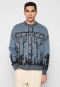 Blauer Strickpullover mit schwarzem abstraktem Muster, Rundhalsausschnitt und gerippten Bündchen. Weiche Textur mit deutlichem visuellem Muster.