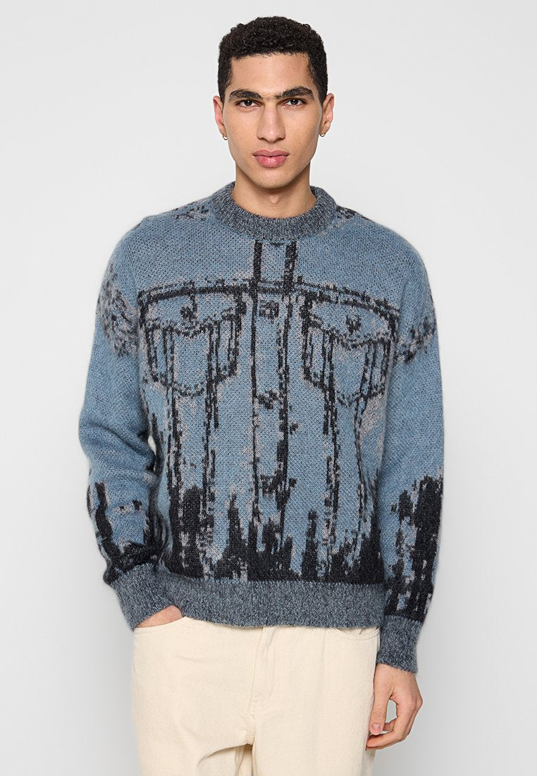 Blauer Strickpullover mit schwarzem abstraktem Muster, Rundhalsausschnitt und gerippten Bündchen. Weiche Textur mit deutlichem visuellem Muster.