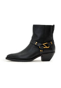Schwarzer Leder-Stiefelette mit niedrigem, schräg gestelltem Blockabsatz, spitz zulaufender Spitze und dekorativer goldfarbener Schnalle und Nieten an seitlichem Riemen.