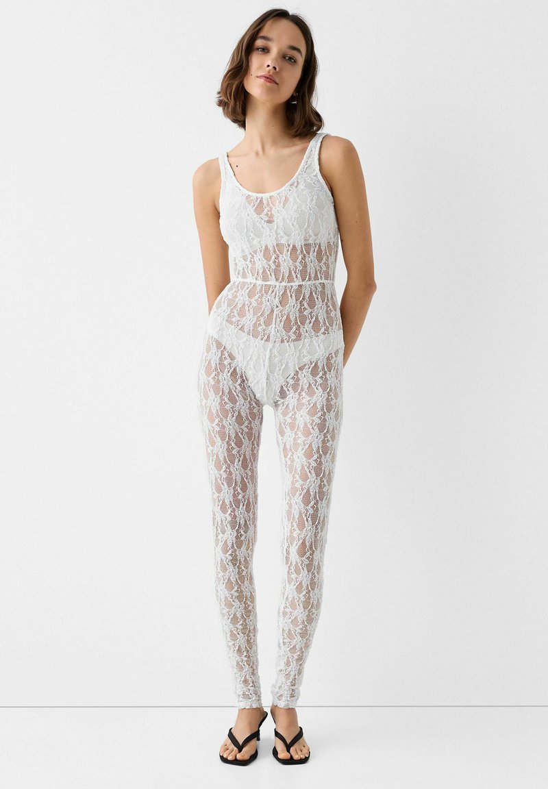 Weißes Body- und Leggings-Set aus Spitze mit filigranen Blumenmustern und figurbetontem Design. Verfügt über einen runden Ausschnitt und minimalen Stoffanteil.