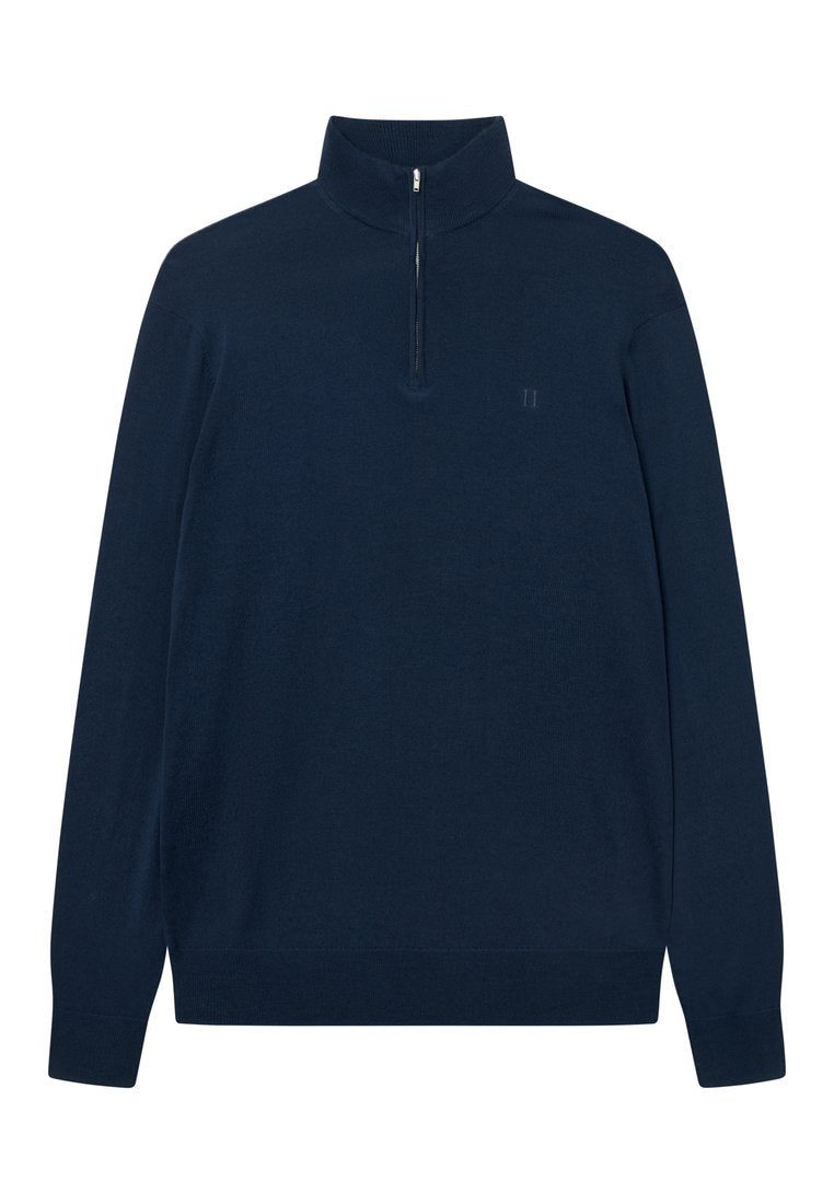 Dunkelblauer, langärmeliger Pullover mit einem halben Reißverschluss am Kragen. Aus weichem Stoff gefertigt, mit einem dezenten Logo auf der linken Brust. Sanfte Textur.