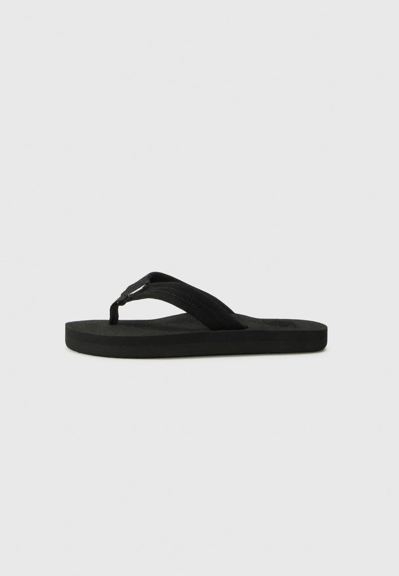 Schwarze Flip-Flop-Sandale mit dicken Stoffriemen und flacher gepolsterter Sohle, seitlich auf einem schlichten weißen Hintergrund präsentiert.