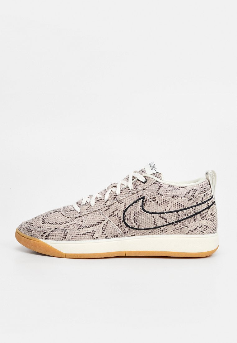 Nike-Sneaker mit Schlangenprint-Muster in Hellbeige und Dunkelbraun, mit weißen Schnürsenkeln und einer Sohle aus Kautschuk. Schwarzes Swoosh-Logo-Detail.