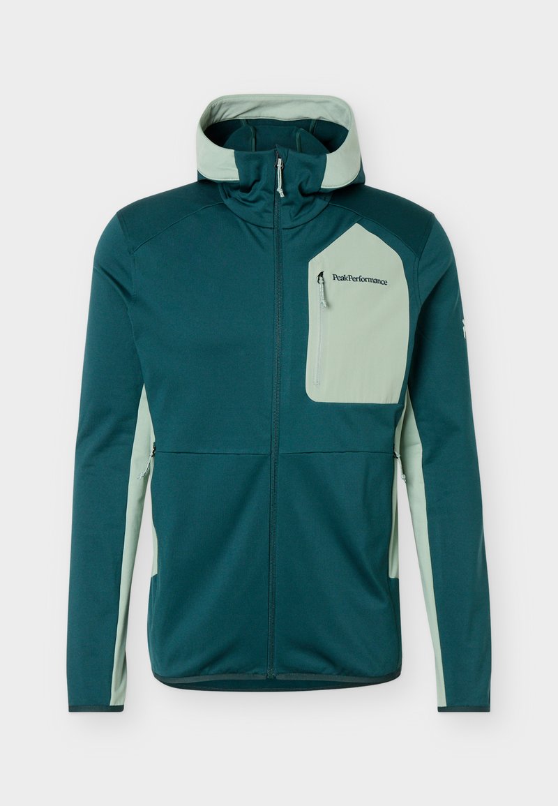 Dunkelgrüne Zip-up-Jacke mit hellgrünem Kapuzenfutter, seitlichen Einsätzen und Brusttasche mit "Peak Performance"-Logo.