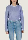 Lavendelfarbener Strickpullover mit strukturiertem Muster, gerippten Bündchen und einem kragen mit weißen Streifen; kombiniert mit hellblauen Jeans.