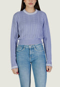 Lavendelfarbener Strickpullover mit strukturiertem Muster, gerippten Bündchen und einem kragen mit weißen Streifen; kombiniert mit hellblauen Jeans.