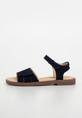 Marineblaue Wildleder-Sandalen mit einem Zehenriemen und verstellbarem Knöchelriemen. Flache Sohle mit braunen Akzenten und strukturierten Details im oberen Bereich.
