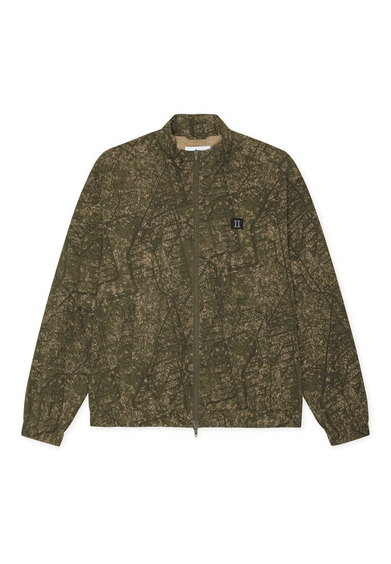 Olivgrüne Zip-Jacke mit abstraktem, dunklem Muster, langen Ärmeln, elastischen Bündchen und kleinem schwarzen Patch mit "II" auf der Brust.