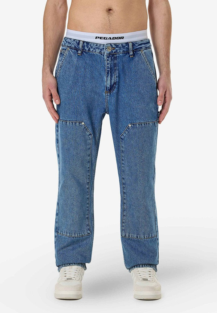 Blaue Jeans aus Denim verfügen über ein gerades Bein-Design mit verstärkten Taschen und einem weißen PEGADOR Bund. Begleitet von weißen Sneakers.