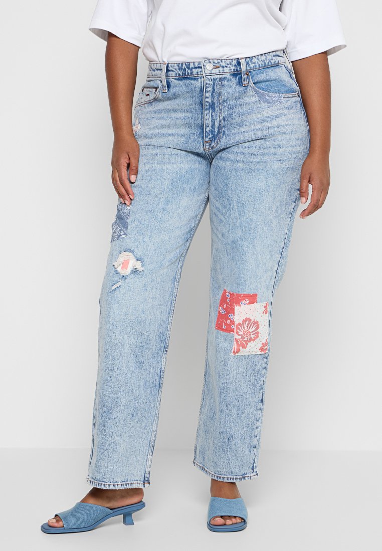 Hellblaue Jeans mit lockerem Schnitt, mit fransigen Kanten und floralen Patches in Rot und Creme. Kombiniert mit blauen Mules.