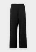 Schwarze, weit geschnittene Hosen aus weichem Stoff, mit einem elastischen Bund und einer glatten Textur ohne Muster oder Akzente.