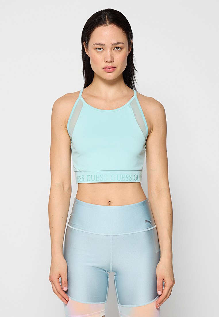 Hellblaues Cropped Top mit dünnen Trägern und einem „GUESS“-Logo-Band. Kombiniert mit hochgeschnittenen, passenden Shorts, ebenfalls in Hellblau.