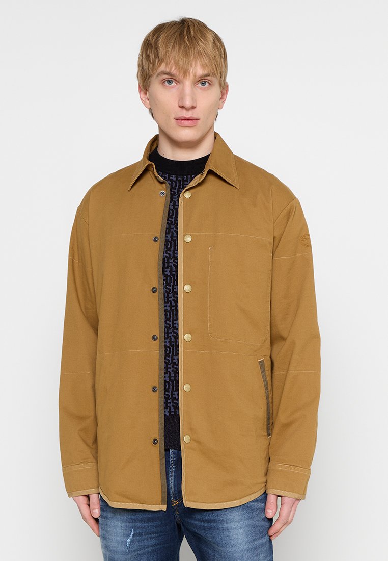Braune, lässige Knopfjacke aus robustem Material. Verfügt über eine Brusttasche, seitliche Taschen und einen Kragen.