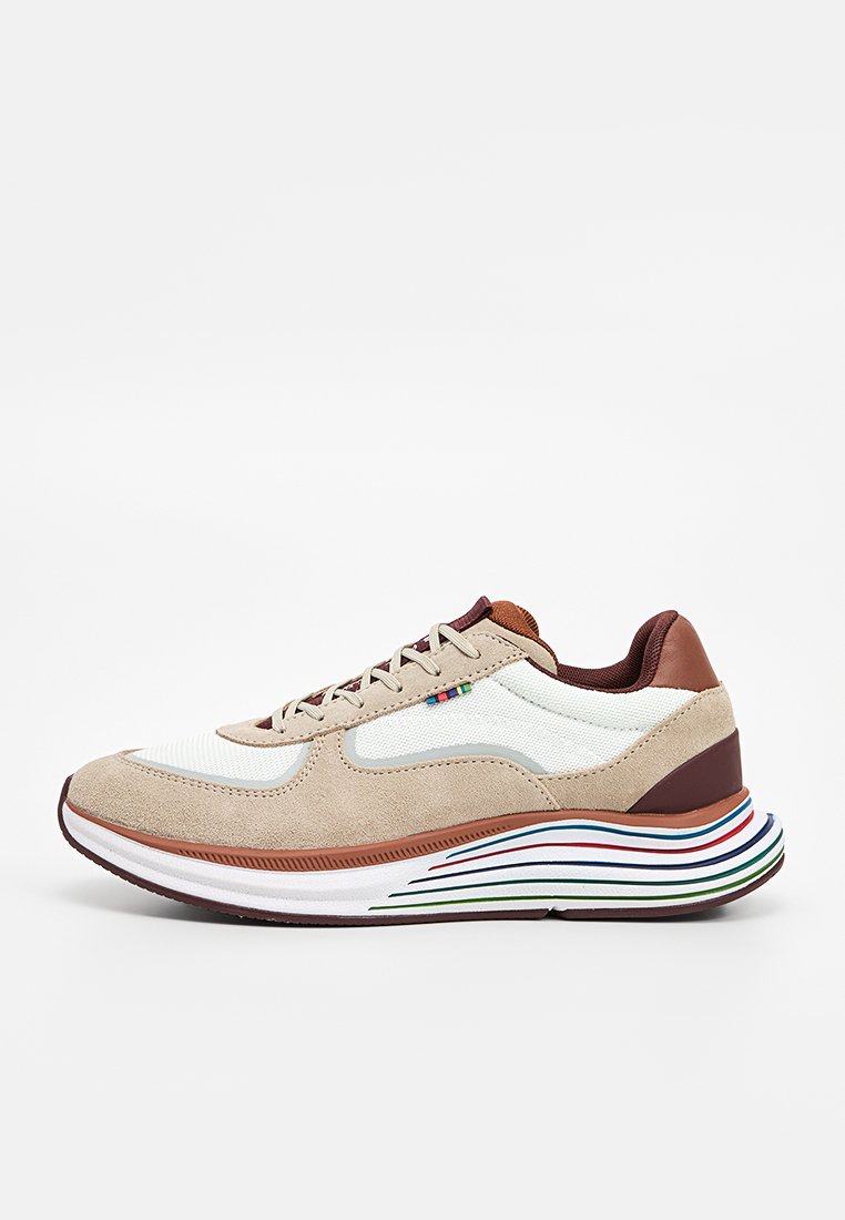 Beige-weißer Sneaker mit braunen Akzenten, weißen Mesh-Einsätzen, mehrfarbigen Streifendetails an der Sohle und Schnürverschluss, Seitenansicht.