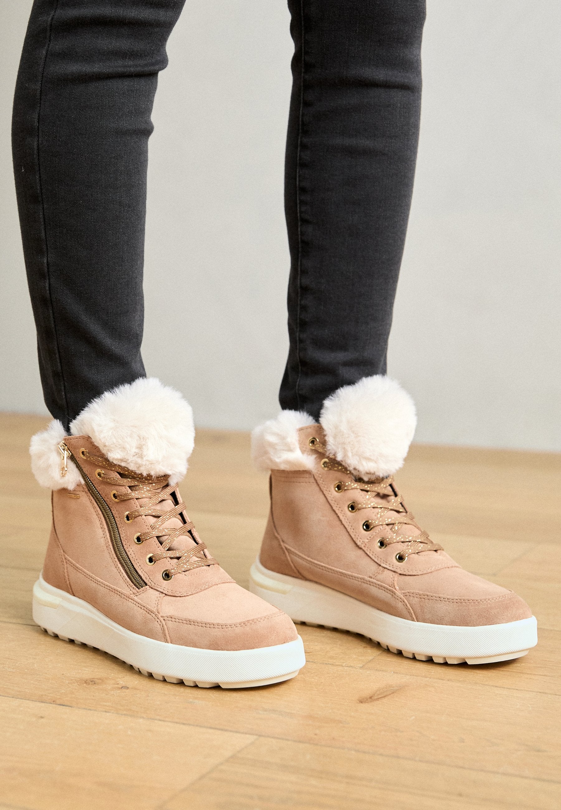 Beige Wildleder-Ankle Boots mit Kunstfellbesatz, goldenen Ösen und Reißverschluss. Dicke weiße Gummisohle, strukturiert für besseren Halt.