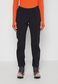 Person trägt schwarze Outdoorhose mit elastischem Bund, leuchtend orangefarbenes Langarmshirt und bunte Wanderschuhe und steht vor einem einfarbigen Hintergrund.
